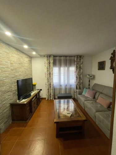Una sala de estar con un sofá y un televisor. en Casa rural los J esuses, en Lillo