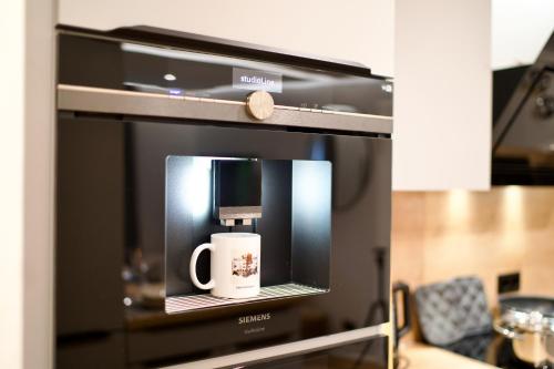 a microwave with a coffee cup on top of it at EDLER WOHNRAUM Noble Stadtoase mit Boxspringbett, Kaffeevollautomat, Lift & Parkplatz in Chemnitz