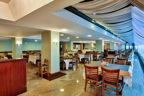 Un restaurante con mesas y sillas en una sala. en Apartamento Rosa en Castelo para Familia, en Campos do Jordão