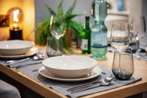 a wooden table with plates and wine glasses on it at EDLER WOHNRAUM Noble Stadtoase mit Boxspringbett, Kaffeevollautomat, Lift & Parkplatz in Chemnitz