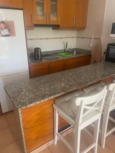 eine Küche mit einer Theke und 2 Hockern in der Unterkunft Jumbo apartment in San Bartolomé de Tirajana