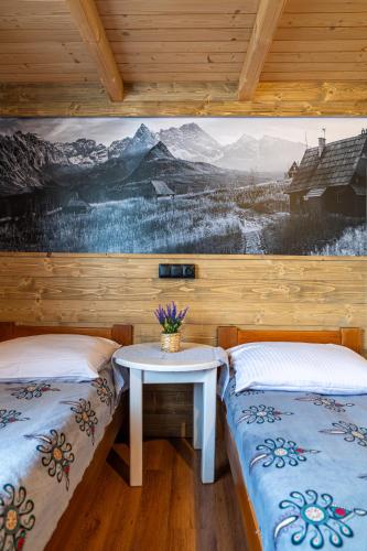 a room with two beds and a table with a painting on the wall at Chatka u Staszka in Małe Ciche
