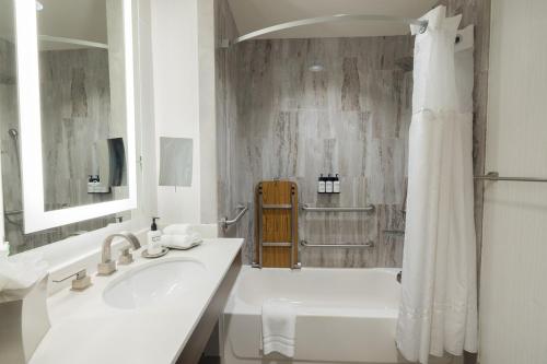 a white bathroom with a sink and a shower at voco Hotel Napoleon Memphis by IHG in Memphis