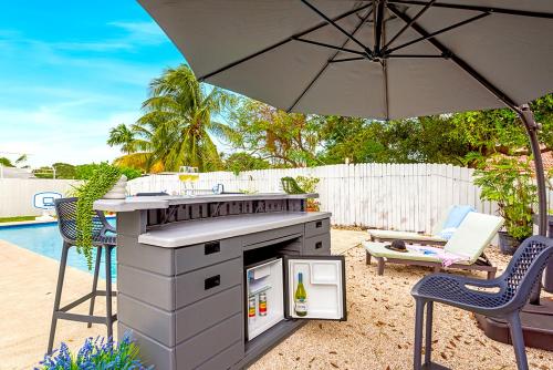 an outdoor grill with an umbrella and chairs and a pool at Family Favorite- Heated Pool, 2 Kings, Everglades in Homestead