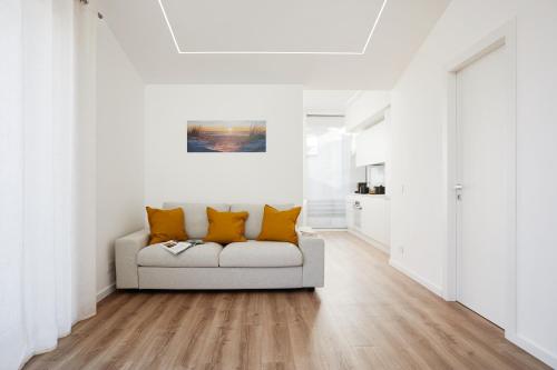 a white living room with a couch with orange pillows at Keys of Sicily - Residence "Sabbia" sul mare in Marina di Modica
