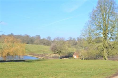 a green field with a pond and a house in the distance at 5 bedroom Manor with idyllic countryside views in Croxton Kerrial