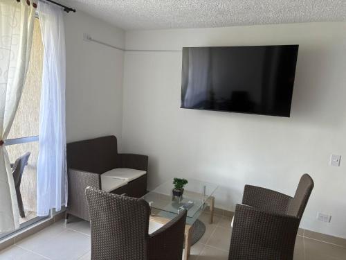 a living room with a table and a television on the wall at Apartamento Apulo Cundinamarca in Apulo