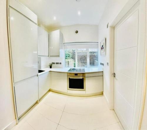a kitchen with white cabinets and a large window at Family flat in Camden, top location, next to attractions in London