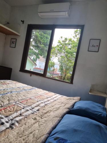 a bedroom with a bed and a large window at Pousada Happy 300m da Praia do Itaguaçú in São Francisco do Sul