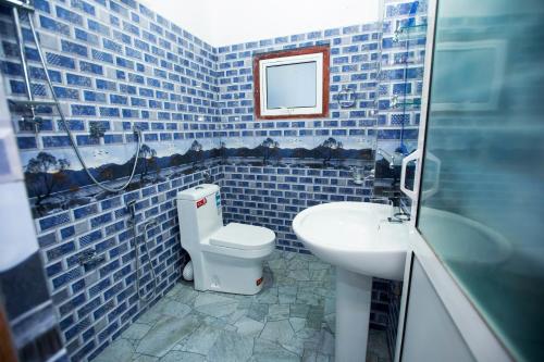 a blue tiled bathroom with a toilet and a sink at Bevary Guest in Anuradhapura