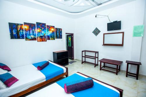 a room with two beds and a flat screen tv at Bevary Guest in Anuradhapura
