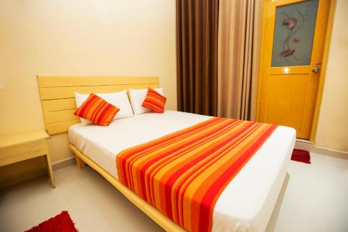 a bedroom with a bed with a colorful striped blanket at Bevary Guest in Anuradhapura
