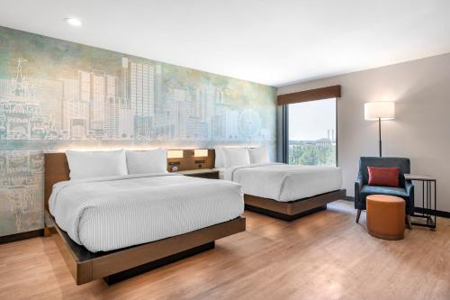 a hotel room with two beds and a chair at Cambria Hotel Orlando near Universal Theme Parks in Orlando