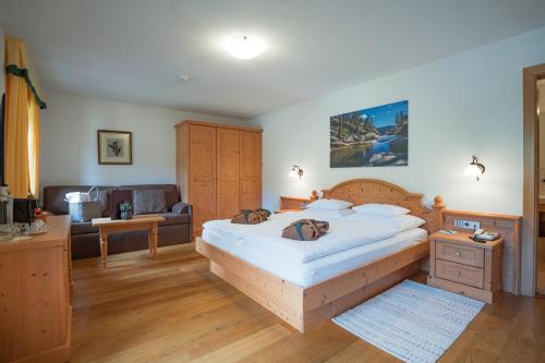 a bedroom with a large bed and a couch at Hotel Weiher Green Lake in Falzes