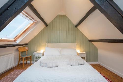 ein Schlafzimmer mit einem weißen Bett auf einem Dachboden in der Unterkunft Bwthyn Beatties in Haverfordwest