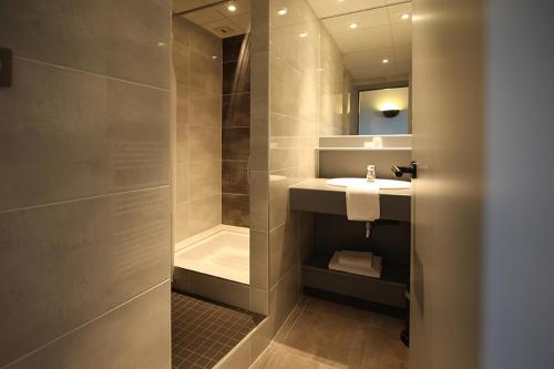 a bathroom with a sink and a shower at Hôtel Restaurant Les Alizés in Lipsheim