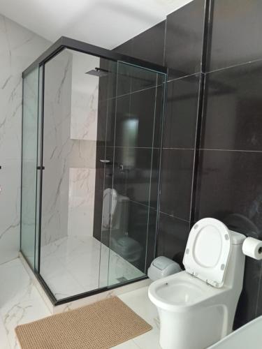 a bathroom with a toilet and a glass shower at Hermosa Casa Vacacional con piscina privada cerca del Aeropuerto in Vila El Carmen