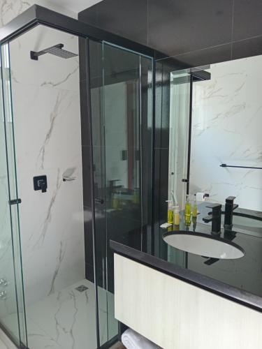 a bathroom with a sink and a glass shower at Hermosa Casa Vacacional con piscina privada cerca del Aeropuerto in Vila El Carmen