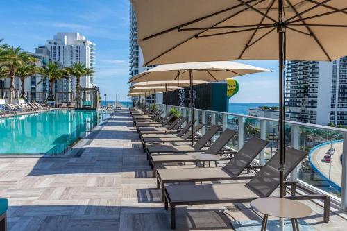 a row of chairs and umbrellas next to a swimming pool at Amazing Apartments at H Beach House in Hollywood