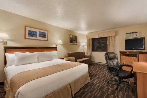 a hotel room with a bed and a desk and a chair at Days Inn by Wyndham Nanaimo in Nanaimo