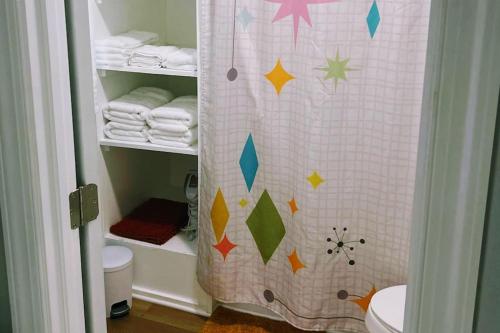 a bathroom with a shower curtain with a toilet and towels at Kitchen, Laundry & Fenced Yard in New Bern