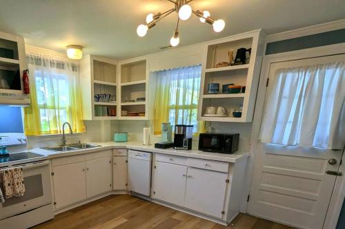 a kitchen with white cabinets and a sink at Kitchen, Laundry & Fenced Yard in New Bern