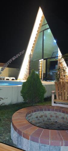 a house with a fire pit in the yard at night at Qafqaz Gabala Twin A Frame Villas in Gabala