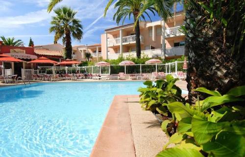 une piscine avec chaises et parasols dans un complexe hôtelier dans l'établissement GOLFE JUAN Joli F2 clim piscine à 5 minutes de la mer, à Vallauris