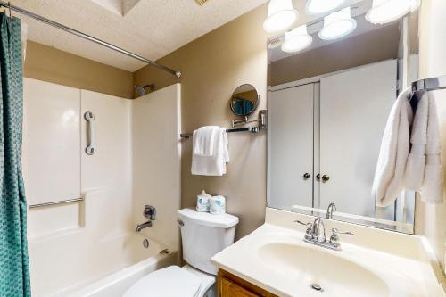 Un baño con lavabo, inodoro y espejo. en Driftwood Towers 2G, en Gulf Shores