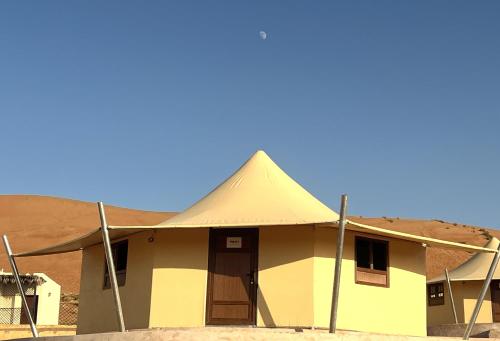 a building with a triangular roof in the desert at Al Salam Desert Camp Bidiya in Bidiyah
