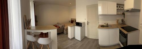 - une petite cuisine avec des placards blancs, une table et des chaises dans l'établissement L'Immeuble de l'Avenue, à Chalon-sur-Saône