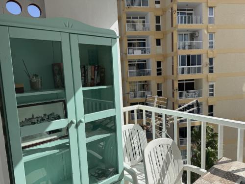 a balcony with white chairs and a glass cabinet at Las Americas Stunning Apartment Close to the Sea in Tenerife in Arona