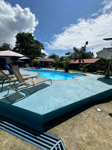 a swimming pool with two lawn chairs and avisorvisor at Hotel Sueños de María in Uvita