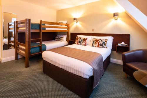 a hotel room with two bunk beds and a chair at The Norfolk Lodge Hotel in Saint Helier Jersey