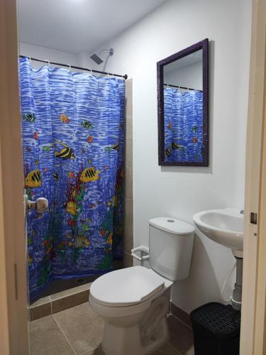 a bathroom with a toilet and a shower curtain at La gran mansión en el centro de Pereira in Pereira
