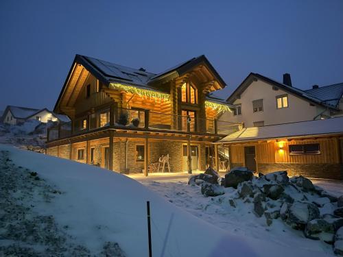a large wooden house in the snow at night at Ferienwohnung Uplandblockhaus in Willingen