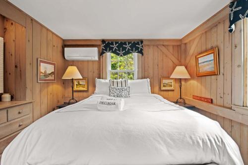 a large white bed in a room with wooden walls at 5 Min Walk to Swimmable Mill Pond Dog Friendly in Orleans