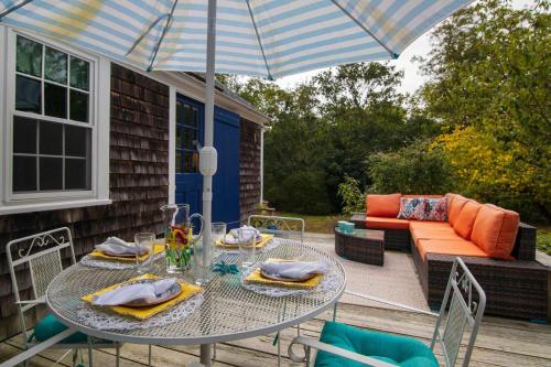 a table and chairs with an umbrella on a patio at 5 Min Walk to Swimmable Mill Pond Dog Friendly in Orleans