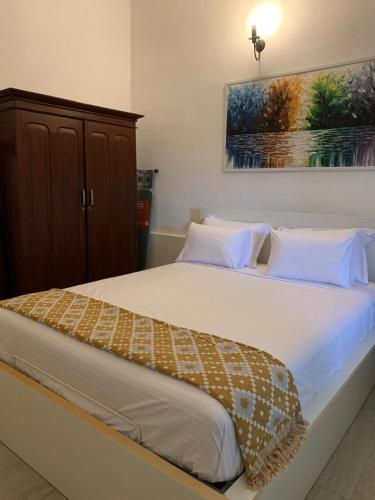 une chambre avec un grand lit avec des draps blancs dans l'établissement Karanda Cottage at Kotte, à Sri Jayewardenepura Kotte