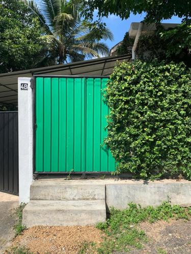un portail vert sur une maison avec une haie dans l'établissement Karanda Cottage at Kotte, à Sri Jayewardenepura Kotte