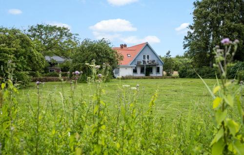 a white house with a red roof in a field at Three-Bedroom Apartment In Broager in Broager