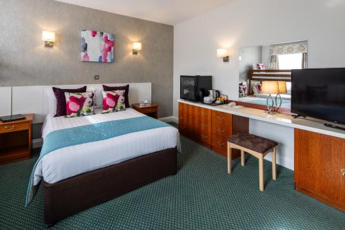 a hotel room with a bed and a desk with a television at The Monterey Hotel - Sure Hotel Collection by Best Western in Saint Helier Jersey