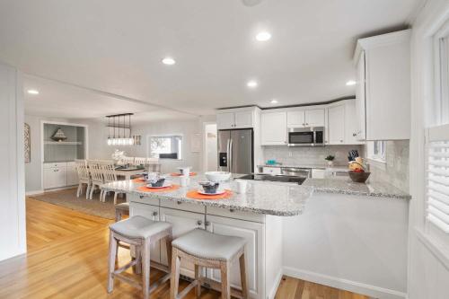 a kitchen with white cabinets and a island with bar stools at 2 Min to Mayflower Beach Dog Friendly in Dennis