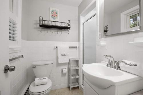 a white bathroom with a toilet and a sink at 2 Min to Mayflower Beach Dog Friendly in Dennis