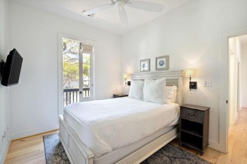 a white bedroom with a bed and a window at Rose Cottage in Rosemary Beach