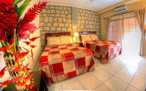 1 dormitorio con 2 camas y pared de piedra en Plaza Magdalena Hotel, en Copan Ruinas