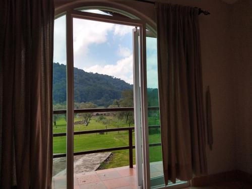 an open glass door with a view of a field at Finca San Fernando in Villa del Carbón