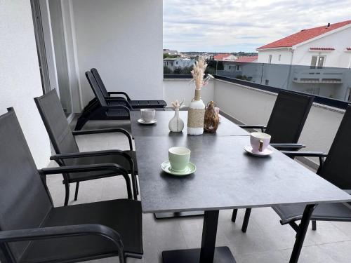 a table and chairs with coffee cups on a balcony at Boutique Hotel IVY'Z in Novalja