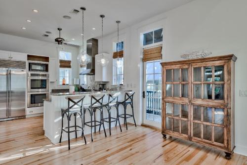 a kitchen with white walls and a wooden island with bar stools at Bella Cottage in Rosemary Beach