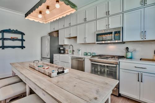 a kitchen with white cabinets and a wooden table at Gilligan's Island in Inlet Beach